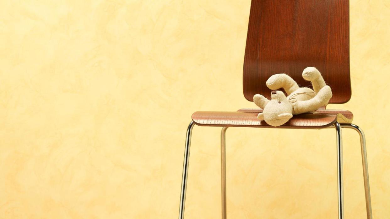 A discard child's teddy bear is seen left on a chair.