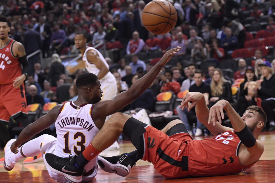 Toronto Raptors centre Jonas Valanciunas (17) makes the pass while on his back as Cleveland Cavaliers forward Tristan Thompson (13) defends during second half NBA basketball action in Toronto on Wednesday, Oct. 17, 2018. (Nathan Denette/The Canadian Press via AP)