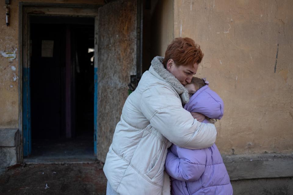 A local woman hugs her daughter in front of their apartment building after their flat was damaged by recent shelling (REUTERS)