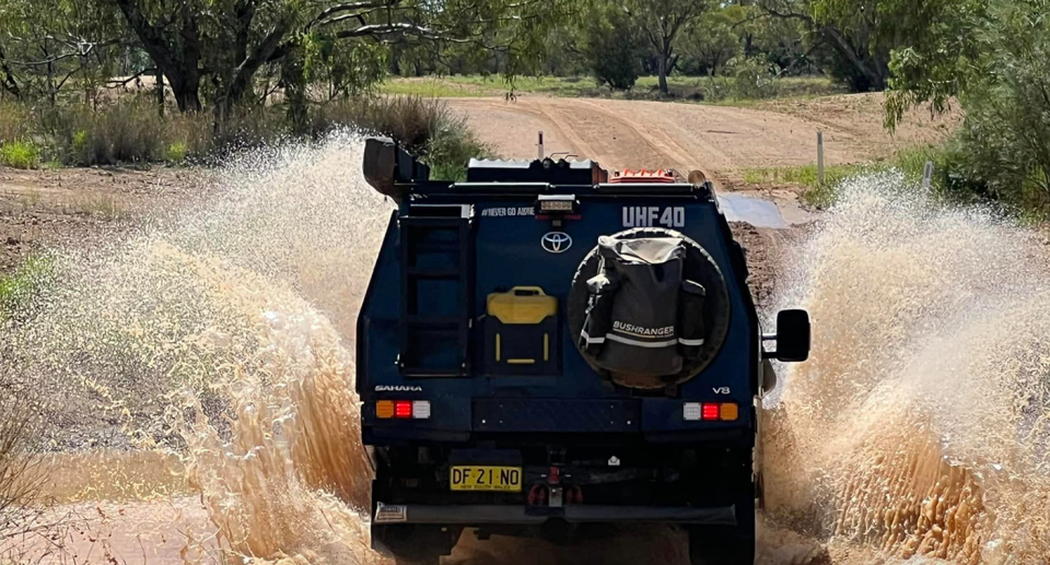 The couple's Toyota Landcruiser driving through a creek.