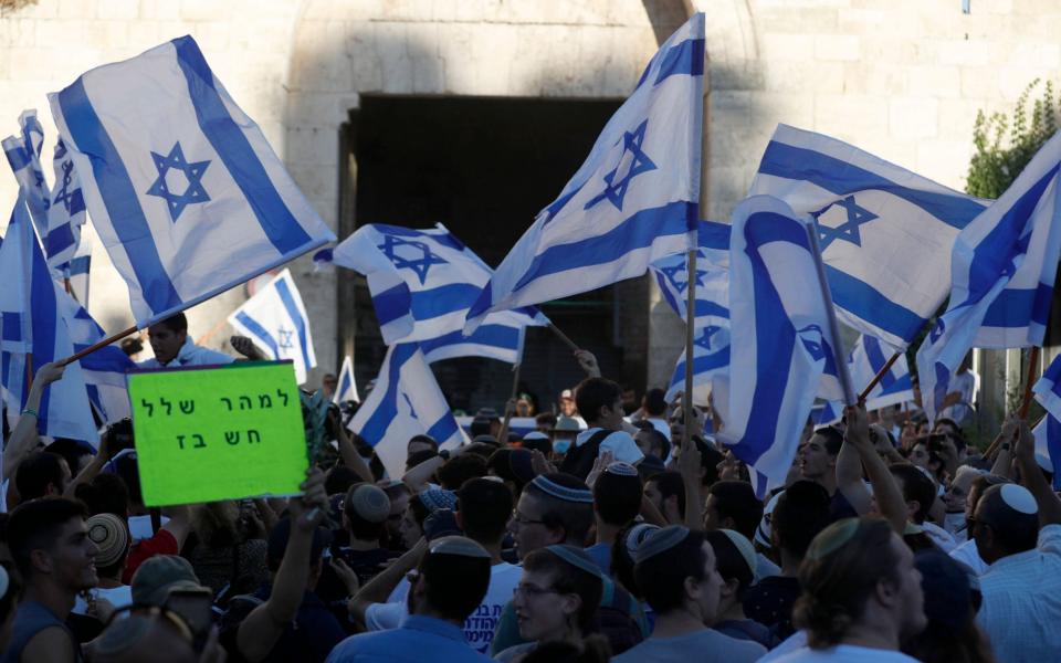 Members of Israeli right-wing groups taking part in the 'Flag March' wave Israeli flags next to Damascus gate of Jerusalem's Old City, 15 June 2021. - Shutterstock