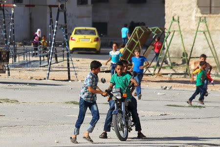 Boys flee from a makeshift playground after hearing the sound of a Syrian fighter jet hovering over Idlib city, Syria July 18, 2015. REUTERS/Ammar Abdullah
