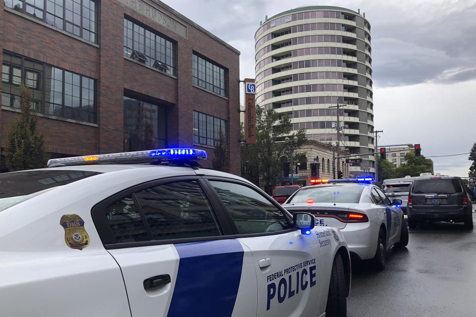 Police respond to a shooting at an apartment building, top rear, in Vancouver, Wash., Thursday, Oct. 3, 2019. Vancouver police say a resident of the building shot several people in the lobby of the Smith Tower Apartments. (AP Photo/Gillian Flaccus)