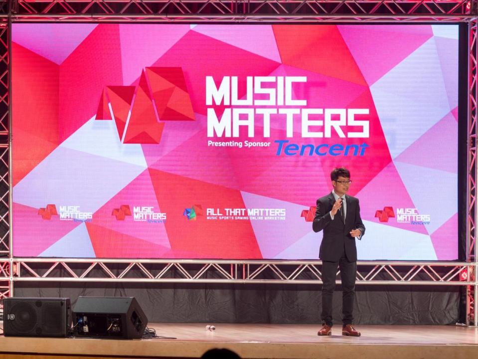 Person on stage with backdrop saying Music Matters with pink and white stripes.