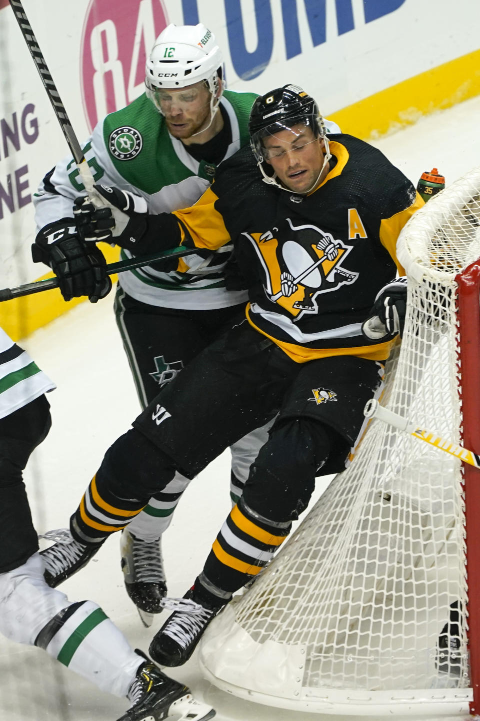 Dallas Stars' Radek Faksa (12) checks Pittsburgh Penguins' Brian Dumoulin into the back of the net during the third period of an NHL hockey game, Tuesday, Oct. 19, 2021, in Pittsburgh. Dallas won 2-1 in a shootout. (AP Photo/Keith Srakocic)