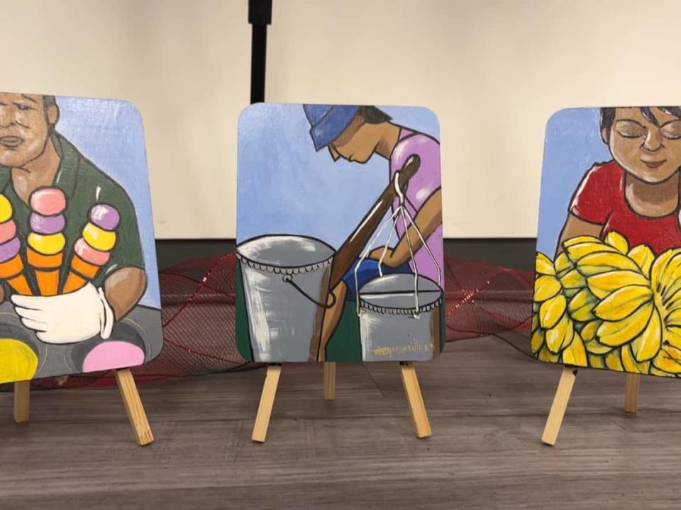 Three miniature artworks stand on the floor under larger paintings at the Philippine Consulate General in Calgary. (Dan McGarvey/CBC - image credit)