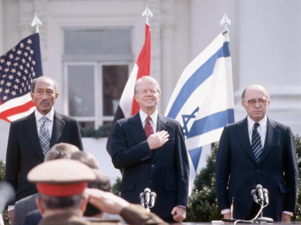 Egyptian President Anwar el-Sadat, US President Jimmy Carter, and Israeli Prime Minister Menachem Begin stand for the three countries' national anthems.