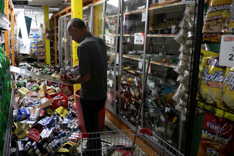 A worker cleans up a shop after an earthquake in Guanica