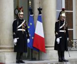 Black bows are attached to the French national flag and the European Union flag (left) at the Elysee Palace in Paris