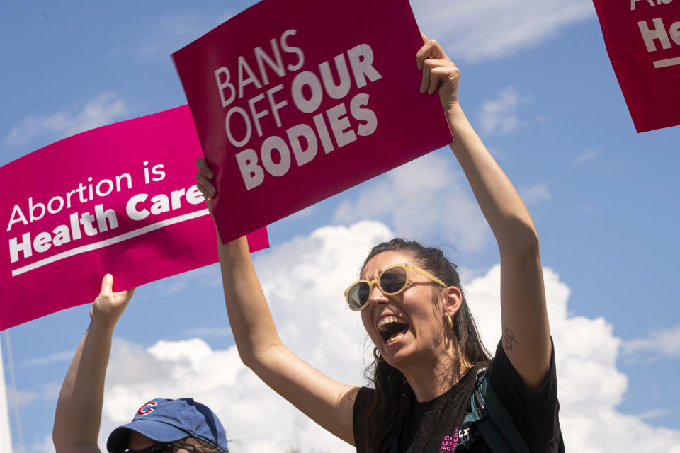 Protesters hold signs reading Bans Off Our Bodies and Abortion Is Health Care.
