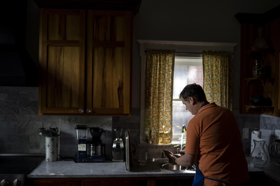 Hollan Holm prepares dinner for his family at his home in Louisville, Ky., Saturday, June 3, 2023. Holm says he told himself that the surface wound he suffered in a 1997 school shooting didn’t justify brooding. More school shootings and the arrival of fatherhood forced him to consider otherwise. (AP Photo/David Goldman)