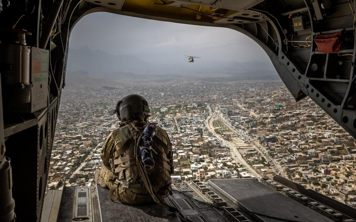 Army soldier aboard a Chinook helicopter looks out over Kabul, Afghanistan, on Sunday, May 2, 2021 - Jim Huylebroek/The New York Times