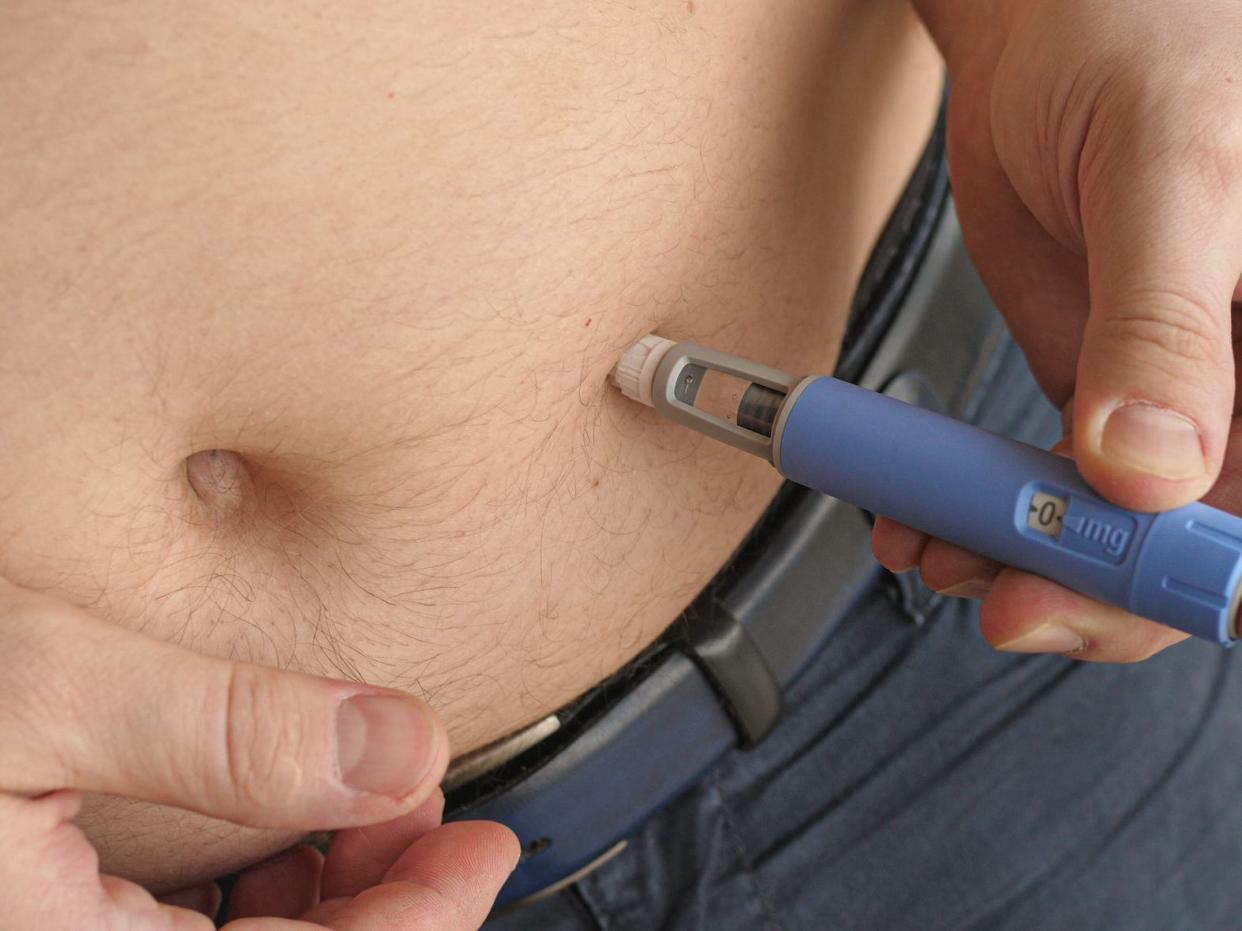 person injecting semaglutide into their belly