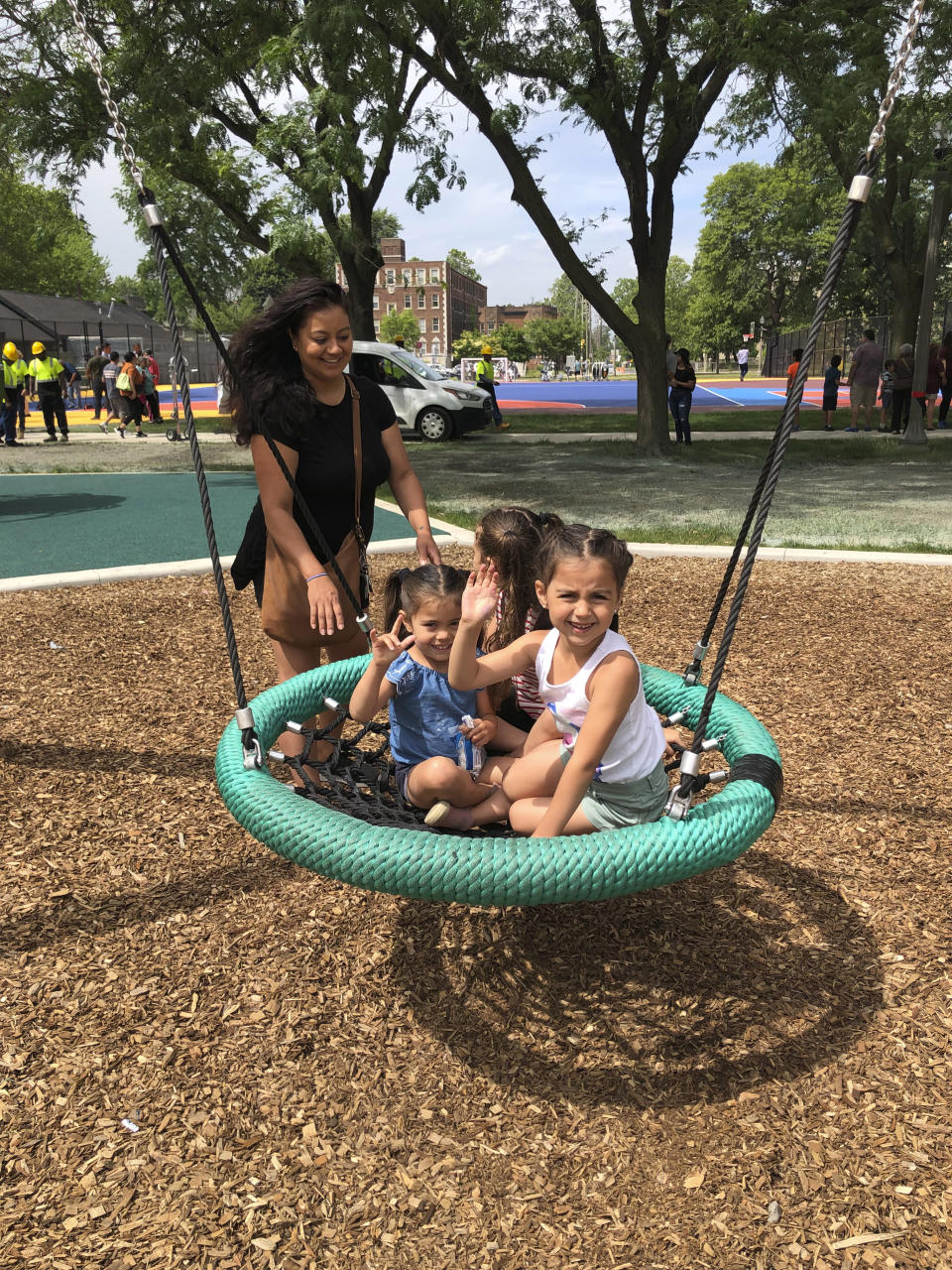 Ariell Kyer plays with her children on a playground in Clark Park on June 22, 2023, in southwest Detroit. Kyer was born in Detroit and now lives in North Carolina. She and her family attended a ribbon cutting for a new splash pad at the park. "There were no parks like what there are now," Kyer said. "Everything is different." (AP Photo/Corey Williams)