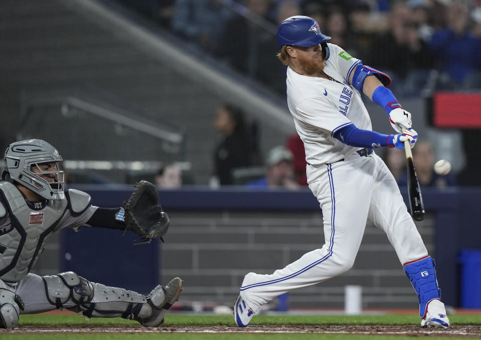 Toronto Blue Jays designated hitter Justin Turner (2) hits an RBI sacrifice fly to center field as New York Yankees catcher Jose Trevino (39) looks on during the third inning of a baseball game in Toronto on Tuesday, April 16, 2024. (Nathan Denette/The Canadian Press via AP)