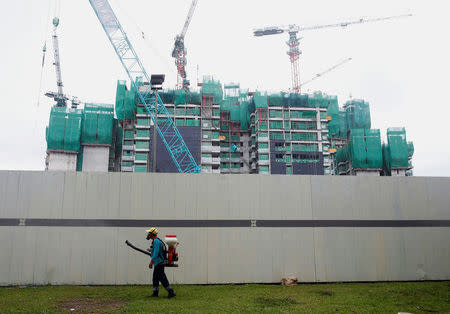 A worker mists with insecticide the perimeter of a construction site, at an area where locally transmitted Zika cases were discovered in Singapore