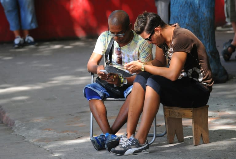 Cubans use their mobile devices to connect to the Internet via wifi in a street in Havana, on July 2, 2015