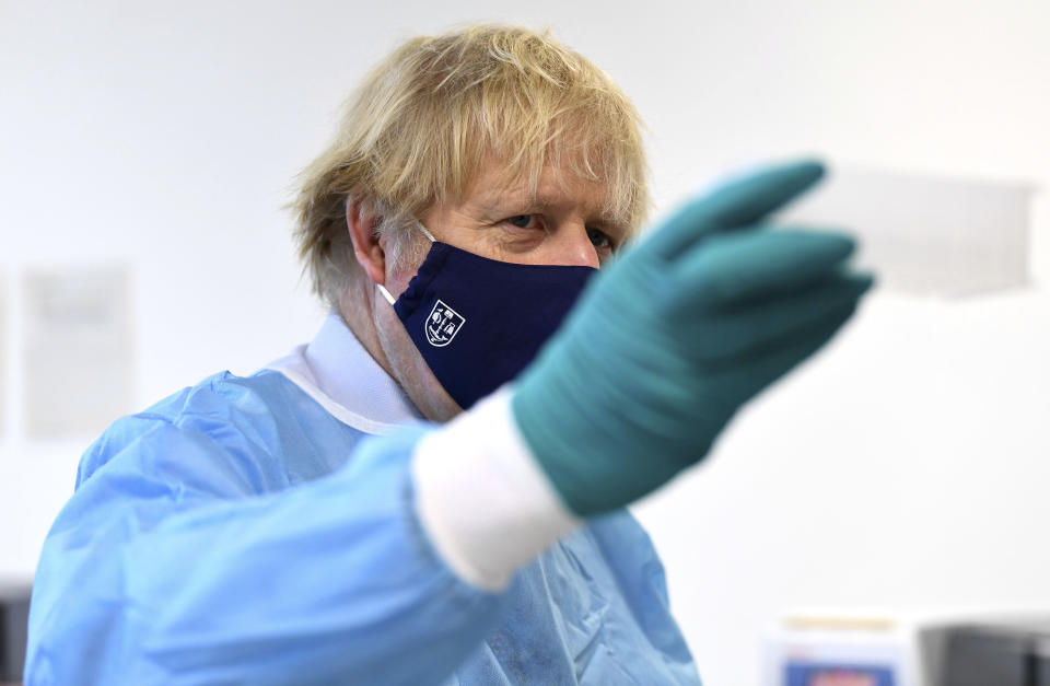 Britain's Prime Minister Boris Johnson, gestures, at the Lighthouse Laboratory, used for processing polymerase chain reaction (PCR) samples for coronavirus, during a visit to the Queen Elizabeth University Hospital campus in Glasgow on his one day visit to Scotland, Thursday, Jan. 28, 2021. Johnson is facing accusations that he is not abiding by lockdown rules as he makes a trip to Scotland on Thursday to laud the rapid rollout of coronavirus vaccines across the United Kingdom. (Jeff Mitchell/Pool Photo via AP)