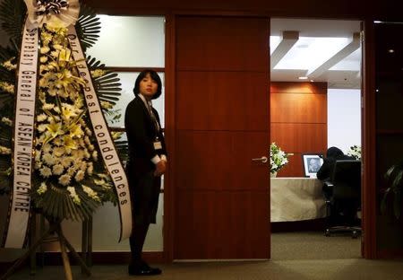 A woman pens a message of condolence in front of a portrait of Singapore's former prime minister Lee Kuan Yew as an employee stands next to a wreath, at the Singapore embassy in Seoul March 23, 2015. REUTERS/Kim Hong-Ji