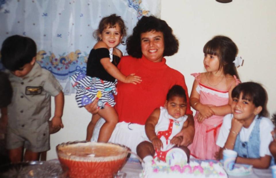 Jamie Acebo holds a friend’s daughter in one arm and holds her baby daughter, Jasmine, steady on the table during a birthday celebration for Jasmine.