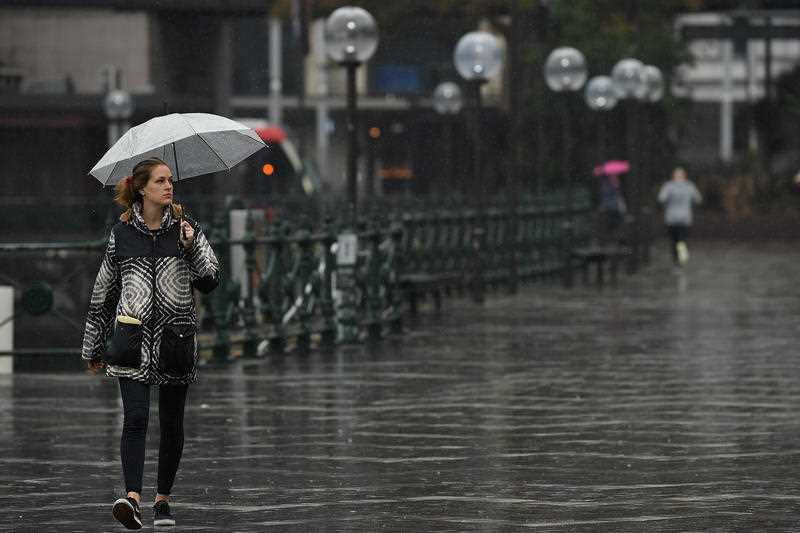 A woman shelters from the rain during wet weather at Circular Quay in Sydney.