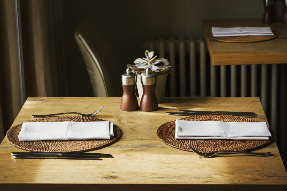 A restaurant table set with silverware and napkins.