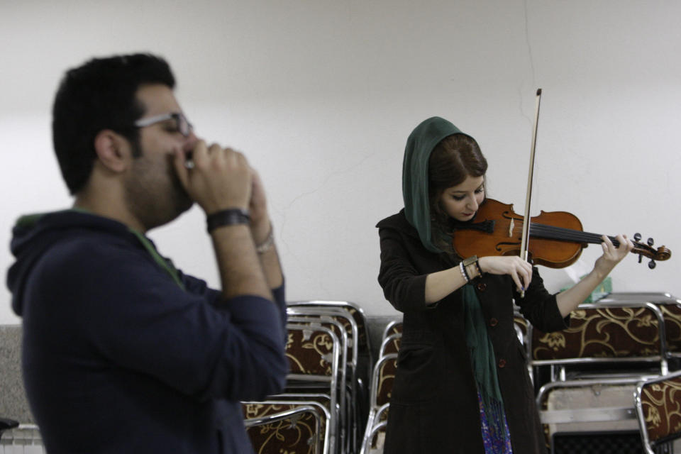 In this picture taken on Friday, Feb. 1, 2013, female Iranian violinist Nastaran Ghaffari and Danial Izadi with his harmonica practice for their band called "Accolade" in a basement of a house in Tehran, Iran. Headphone-wearing disc jockeys mixing beats. Its an underground music scene that is flourishing in Iran, despite government restrictions. (AP Photo/Vahid Salemi)