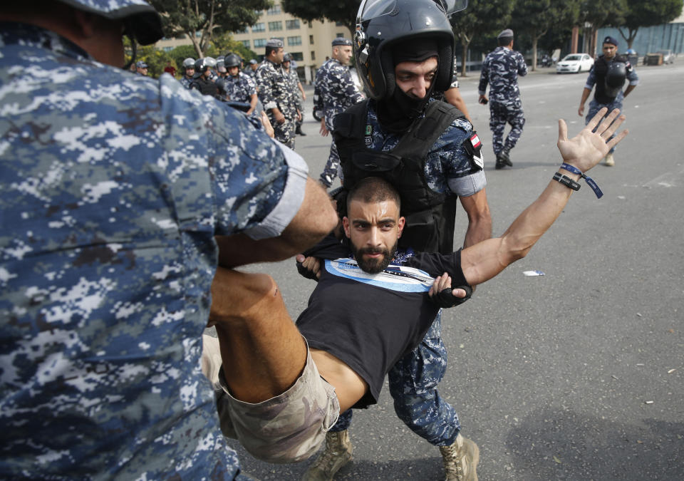 Riot police remove an anti-government protester blocking a main highway with his body in Beirut, Lebanon, Saturday, Oct. 26, 2019. The removal of the roadblocks on Saturday comes on the tenth day of protests in which protesters have called for civil disobedience until the government steps down. (AP Photo/Hussein Malla)