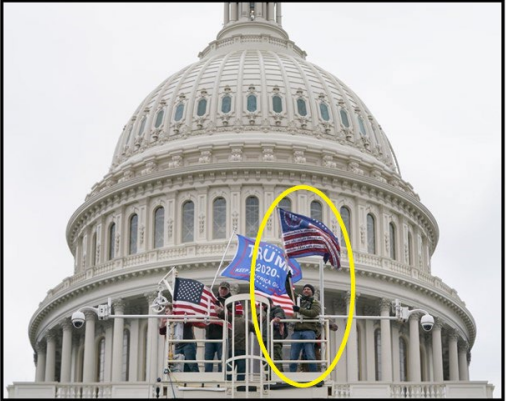 Image 7: The subject atop a media tower waving a “Three Percenters” flag (US DOJ).
