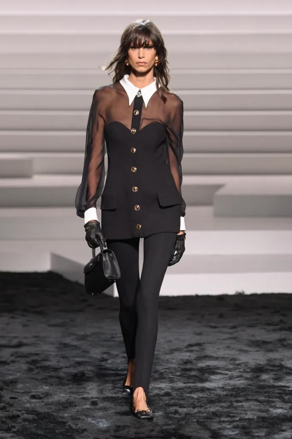 Versace fall 2024 runway model wearing sheer black top with gold buttons and white peter pan collar and cuffs