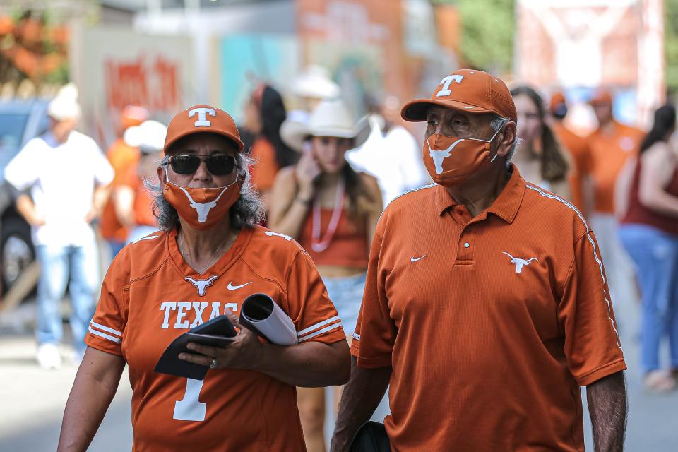 University of Texas fans Gloria Ramos, left, and Robert Ramos of Weslaco walk through the outdoor festivities before the Longhorns' opening game last year. This weekend's opening game will be happening with Austin at lower levels of COVID-19 spread.