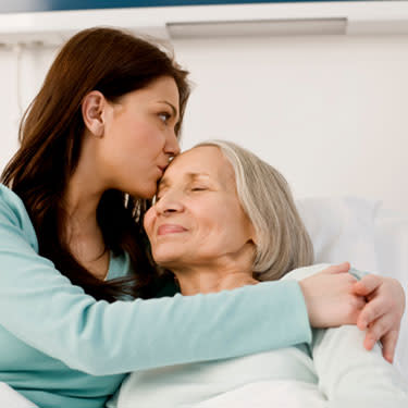 Woman kissing patient in bed web