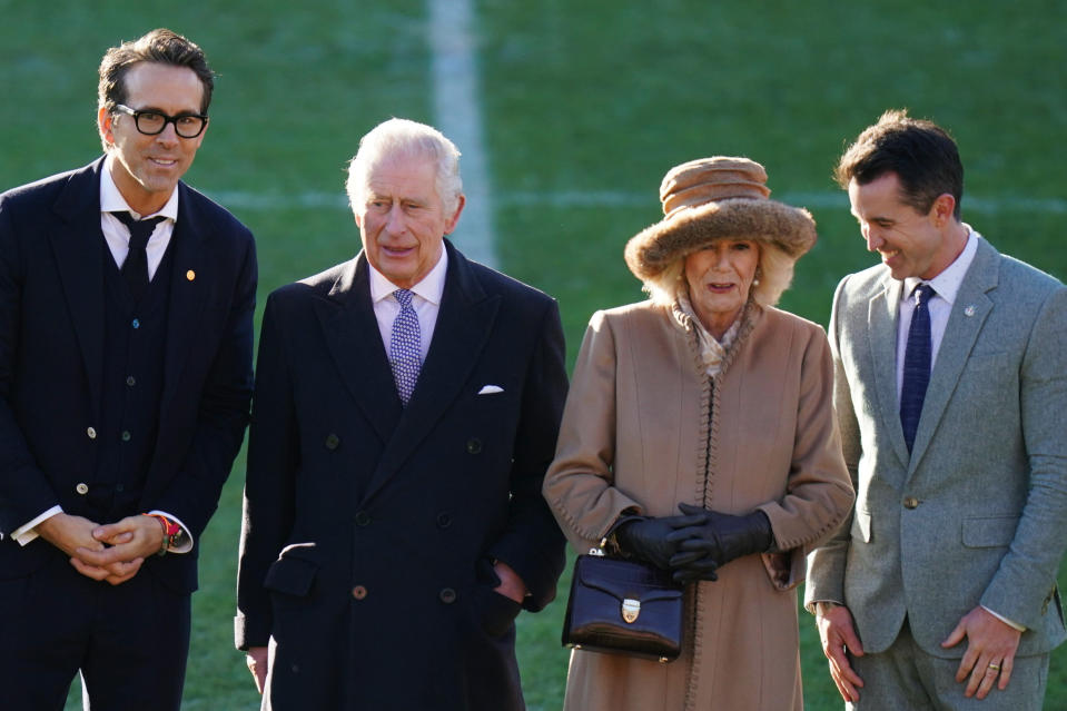 Britain's King Charles III and centre left and Camilla, the Queen Consort, centre right speak to Wrexham Soccer team co owners, US actors Ryan Reynolds, left and Rob McElhenney during their visit to Wrexham Association Football Club's Racecourse Ground, in Wrexham, England, Friday, Dec. 9, 2022. (Jacob King/PA via AP)