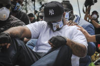 An emotional Terrence Floyd is comforted as he sits at the spot at the intersection of 38th Street and Chicago Avenue, Minneapolis, Minn., where his brother George Floyd, encountered police and died while in their custody, Monday, June 1, 2020. (AP Photo/Bebeto Matthews)