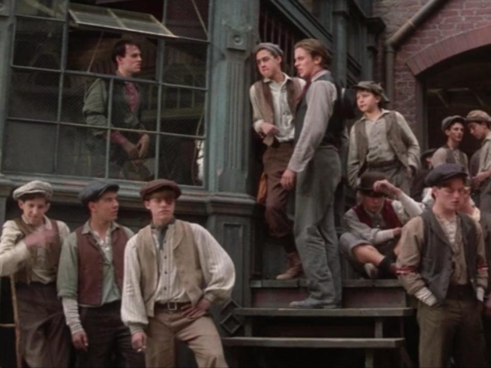 The newsboys in Newsies sitting by where the papers are sold