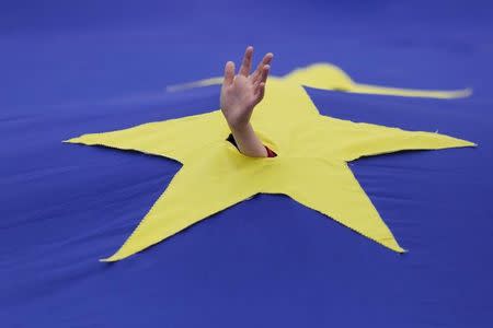 A child waves his hand through a cut made in one of the stars that make up the European Union flag, during a support rally organised to mark the EU's 60th anniversary of the Treaty of Rome in downtown Bucharest, Romania, March 25, 2017. Inquam Photos/Octav Ganea/via REUTERS