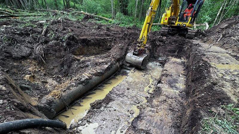 A digger removing earth around a water pipe