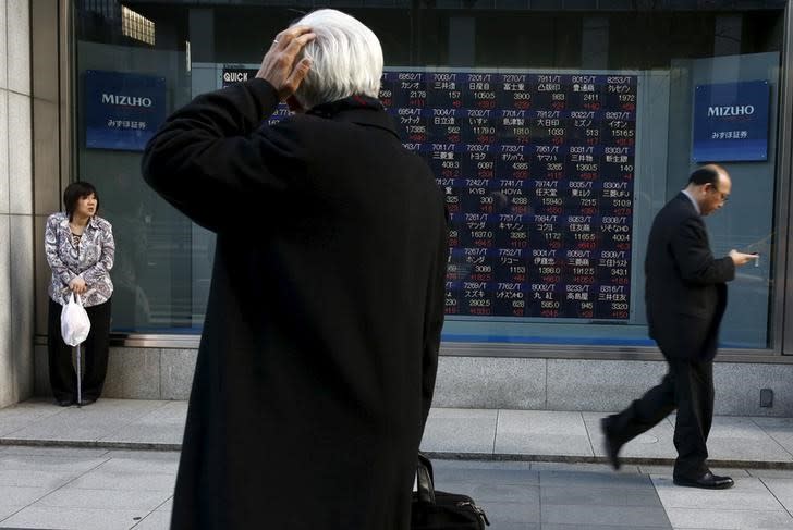 FILE PHOTO: A man looks at an electronic board showing market indices outside a brokerage in Tokyo, Japan, March 2, 2016. REUTERS/Thomas Peter