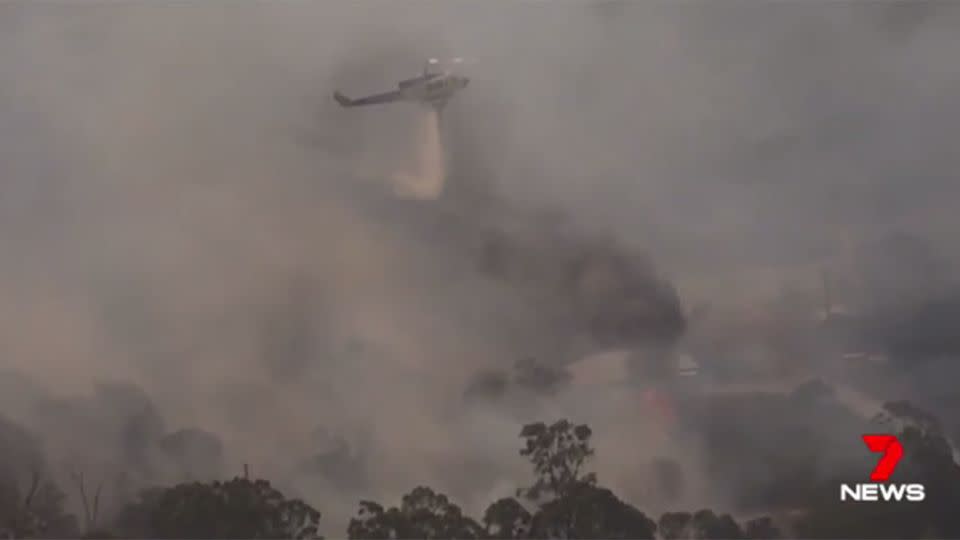 Moments later a high-powered helicopter emerged from the black smoke dropping more than two tonnes of water. Source: 7 News