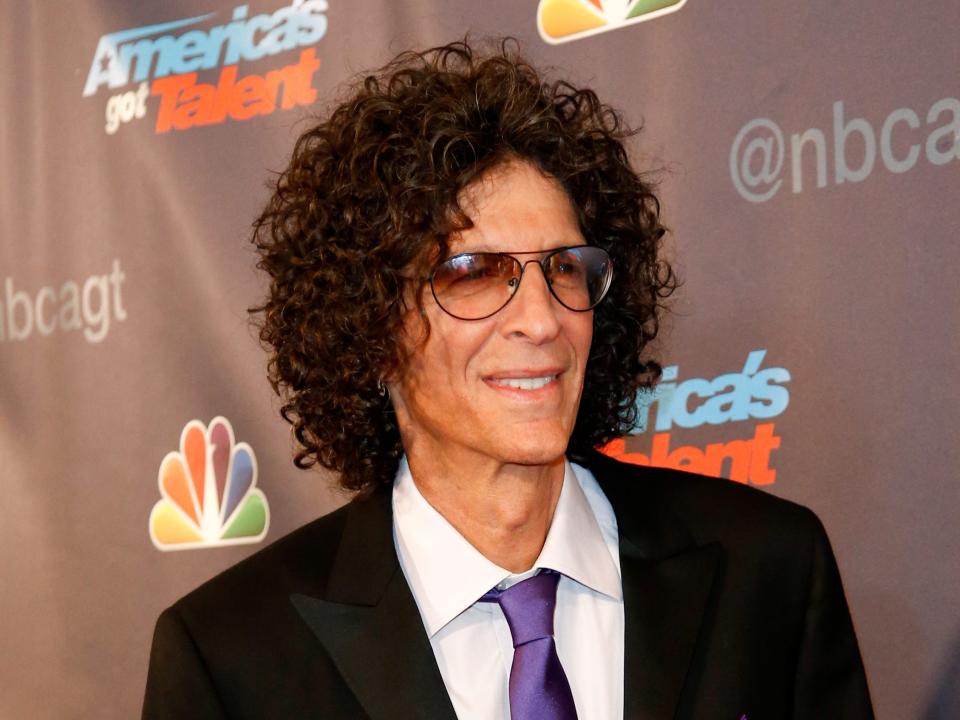 Howard smiling with glasses and curly hair and a suit.