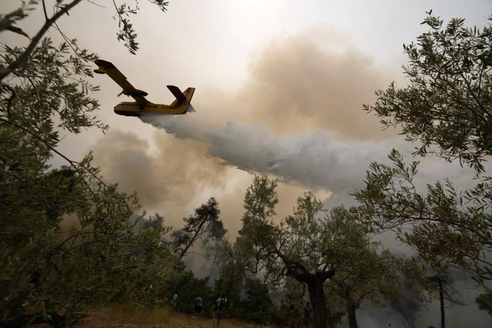 An aircraft drops water over a wildfire at Ellinika village on Evia island, about 176 kilometers (110 miles) north of Athens, Greece, Monday, Aug. 9, 2021. Firefighters and residents battled a massive forest fire on Greece's second largest island for a seventh day Monday, fighting to save what they can from flames that have decimated vast tracts of pristine forest, destroyed homes and businesses and sent thousands fleeing. (AP Photo/Petros Karadjias)