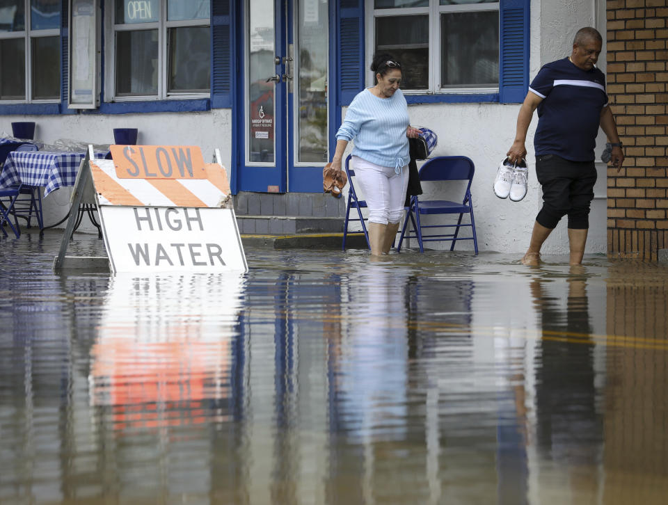 An unidentified couple wade through flood waters along the sidewalk of Dodecanese Boulevard Thursday, April 11, 2024 in Tarpon Springs, Fla. (Chris Urso/Tampa Bay Times via AP)