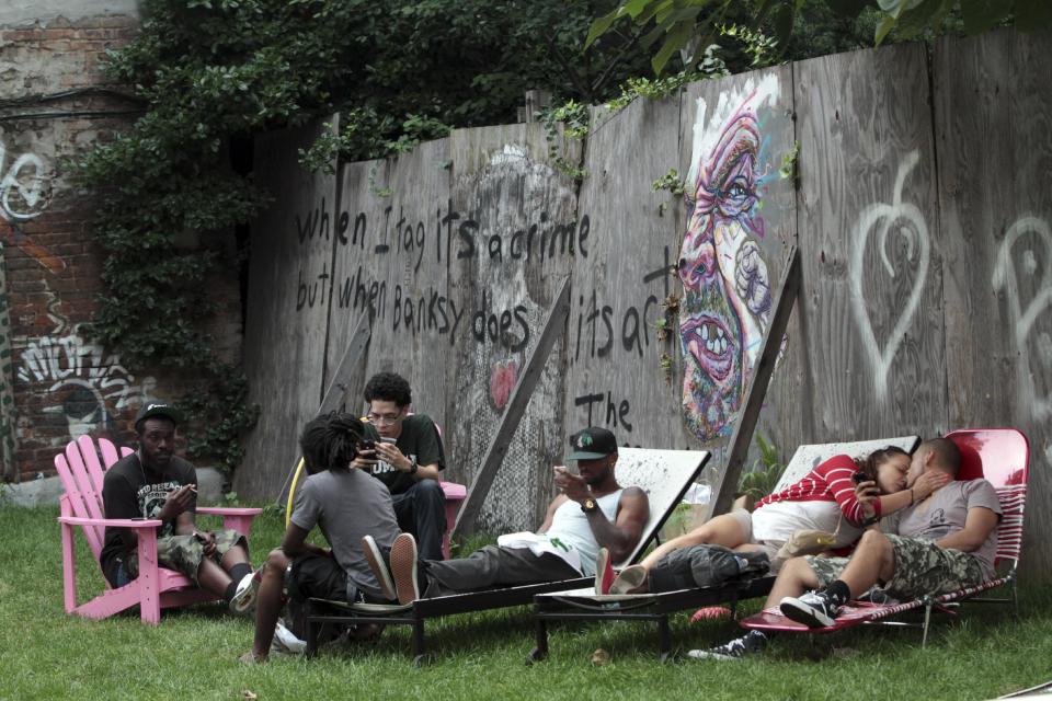 In this Wednesday, July 25 2012 photo, a group of people use the lounge chairs at Timeshare Backyard on the Lower East Side of Manhattan. The city's lone timeshare backyard allows New Yorkers to invite up to 30 guests for two hours at a time and comes with grills, lounge chairs and trashy magazines. (AP Photo/Mary Altaffer)