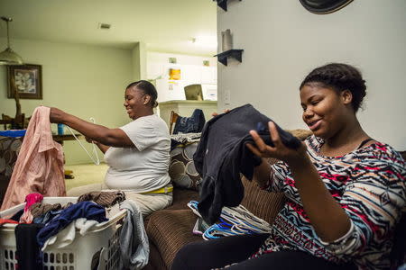 Qumotria Kennedy (L) and her daughter Victorya Ricks fold laundry and watch television in the evening in this handout photo provided by American Civil Liberties Union (ACLU) October 21, 2015, in D'Iberville, Mississippi, October 6, 2015. REUTERS/William Widmer/UCLA/Handout via Reuters