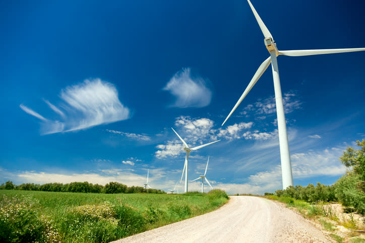 A road with wind turbines along its path.