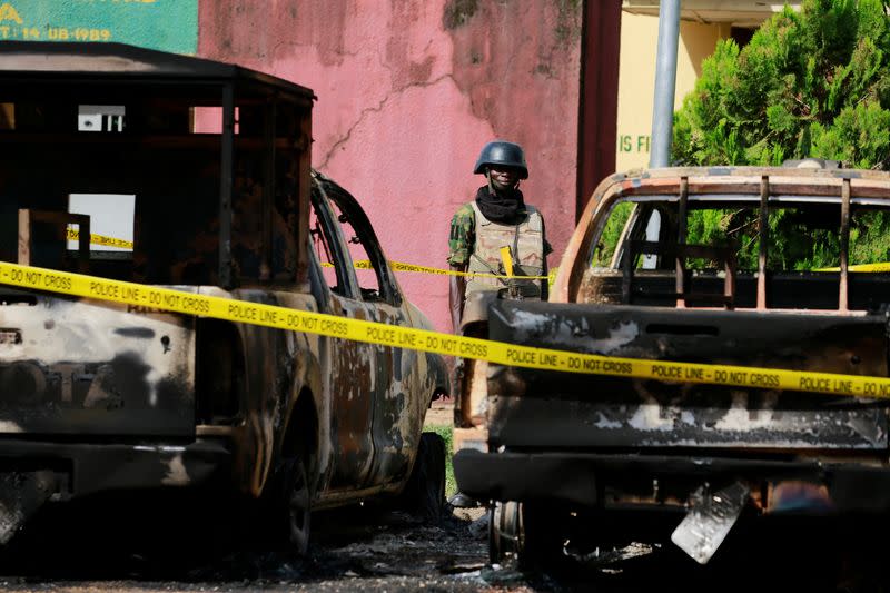 A soldier stands guard between burnt vehicles during Nigeria's President Muhammadu Buhari's visit to the Kuje prison, in Abuja