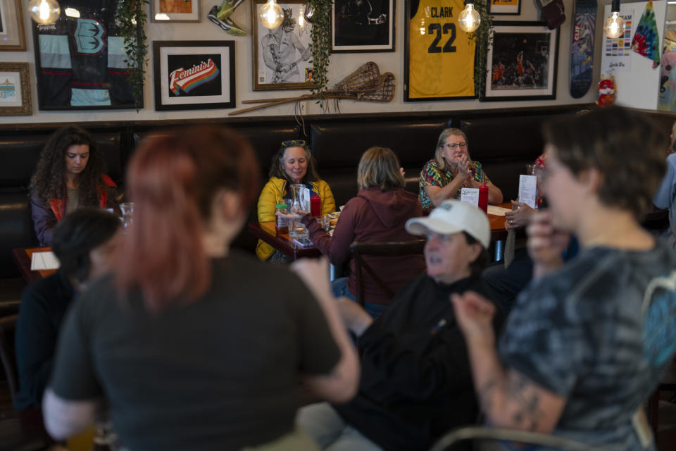 As a Caitlin Clark jersey is displayed in the background, customers eat and watch college women's lacrosse and beach volleyball matches at The Sports Bra sports bar on Wednesday, April 24, 2024, in Portland, Ore. Interest in women's sports is at an all-time high, helped by Clark's exploits this year, when she shattered all-time NCAA scoring records for both women and men. (AP Photo/Jenny Kane)