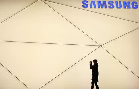 A woman takes a picture outside the Samsung stand at the Mobile World Congress in Barcelona February 24, 2014. REUTERS/Albert Gea