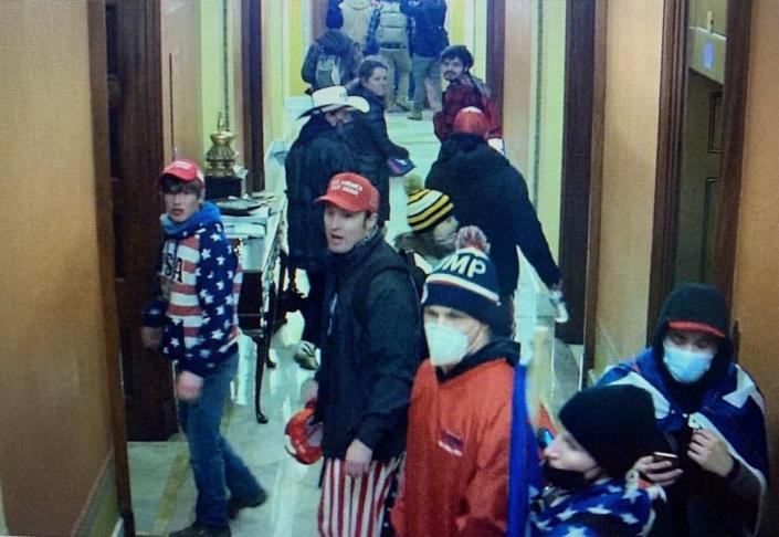 Zachary Wilson, in red jacket and face mask, is seen at the Capitol on Jan. 6. Federal court documents