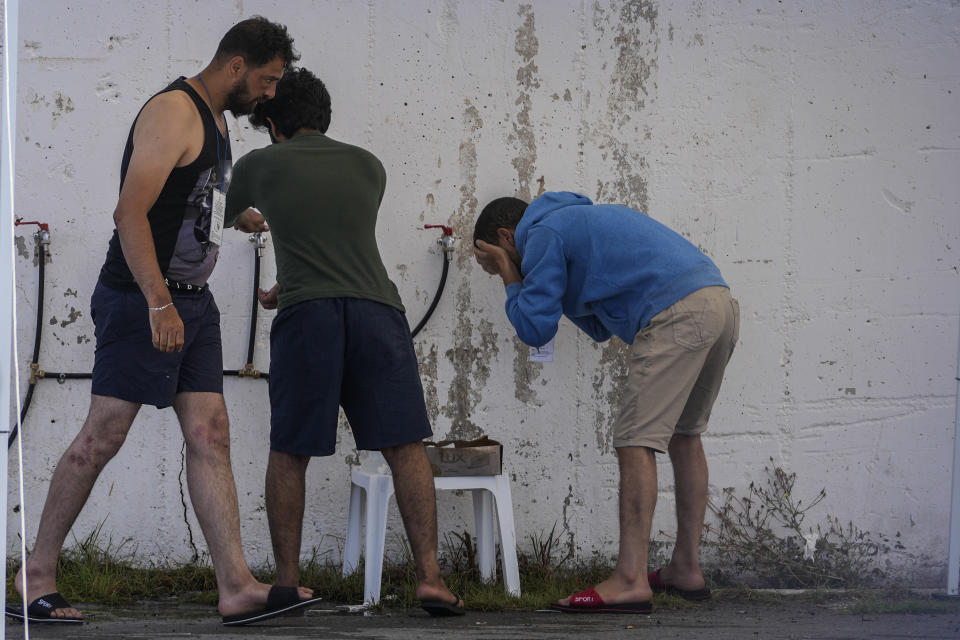 Survivors of a shipwreck wash their selves outside a warehouse at the port in Kalamata town, about 240 kilometers (150miles) southwest of Athens, Greece, Thursday, June 15, 2023. A fishing boat crammed to the gunwales with migrants trying to reach Europe capsized and sank Wednesday June 14 off the coast of Greece, authorities said, leaving at least 79 dead and many more missing in one of the worst disasters of its kind this year. (AP Photos/Thanassis Stavrakis)